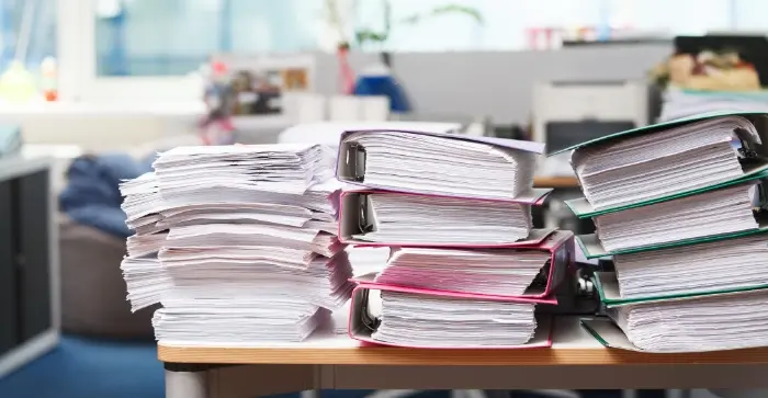 企業内で、大量の紙文書が積みあがっている様子
